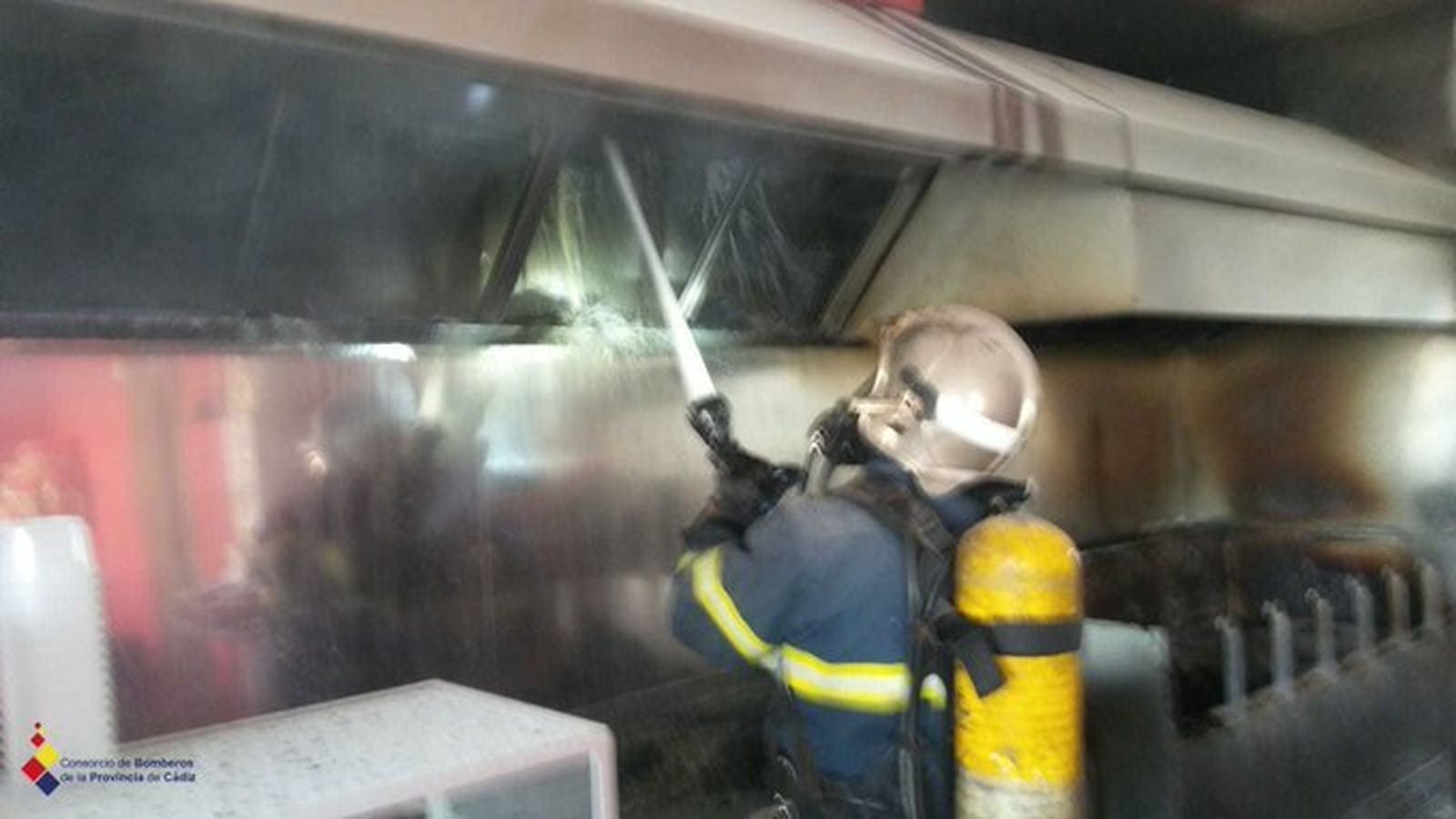 Un bombero sofoca el incendio en la campana extractora de humos.