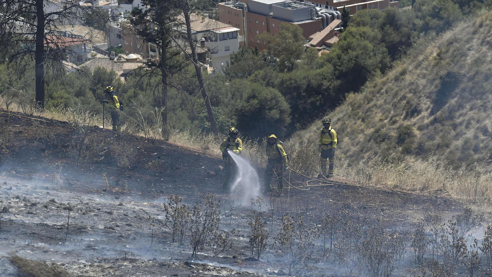 Bomberos refrescan con agua una zona quemada