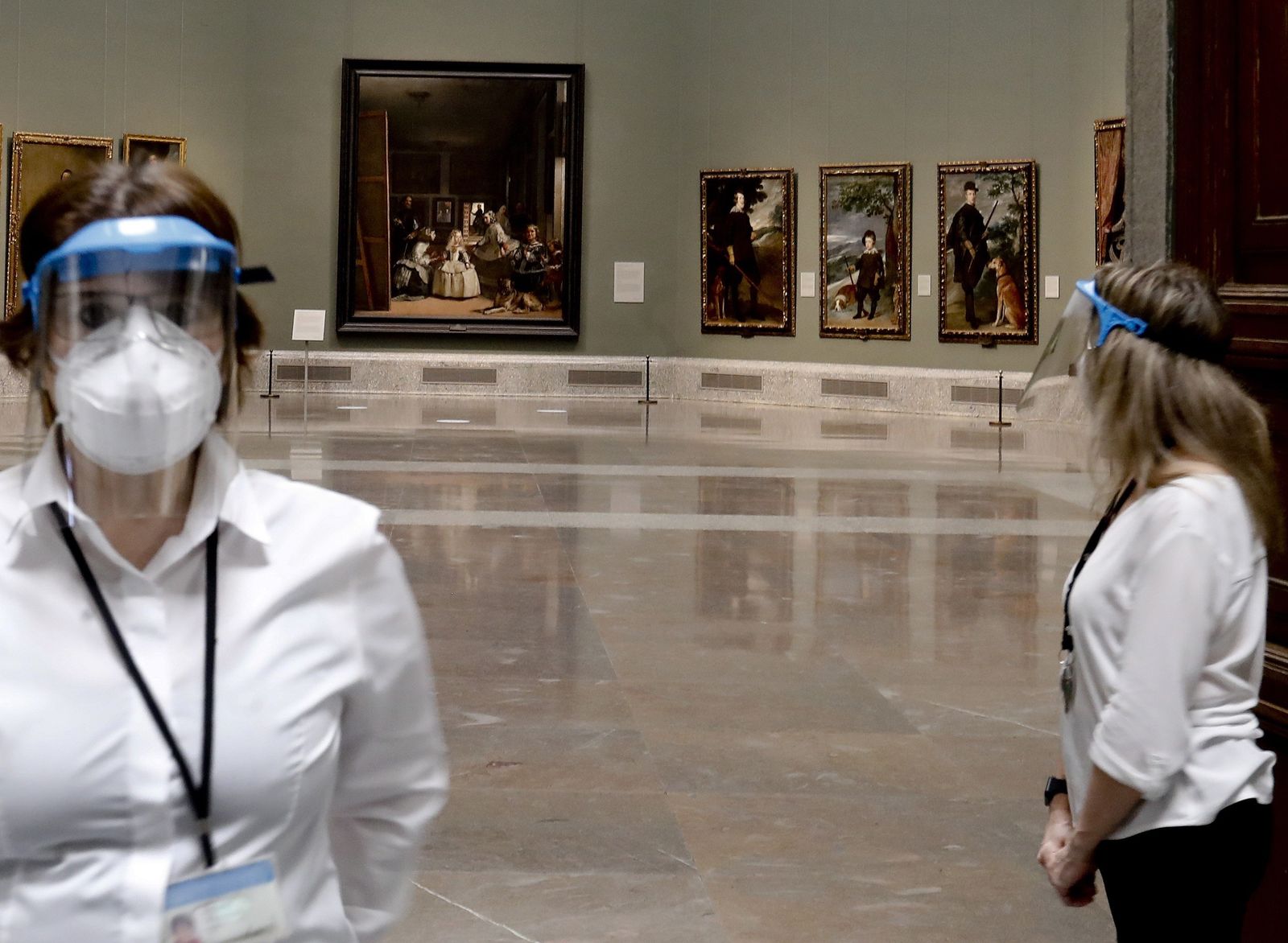 Dos trabajadoras del Prado, con mascarillas, con 'Las Meninas' al fondo.