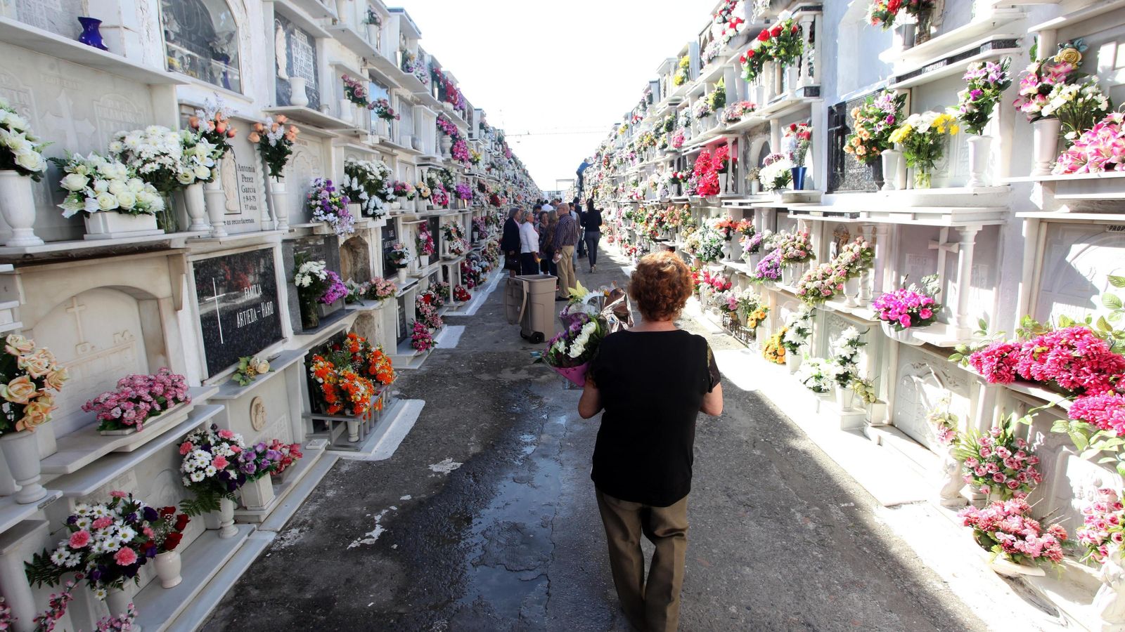 Familiares y amigos visitan a sus seres queridos en un cementerio con motivo del Día de los Santos.