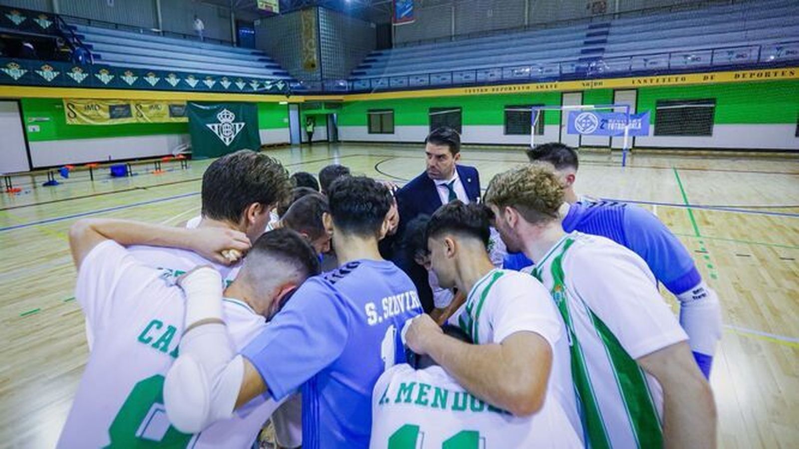 Ramón Martínez, al fondo, se suma a una piña de sus futbolistas previa a un partido del filial verdiblanco.