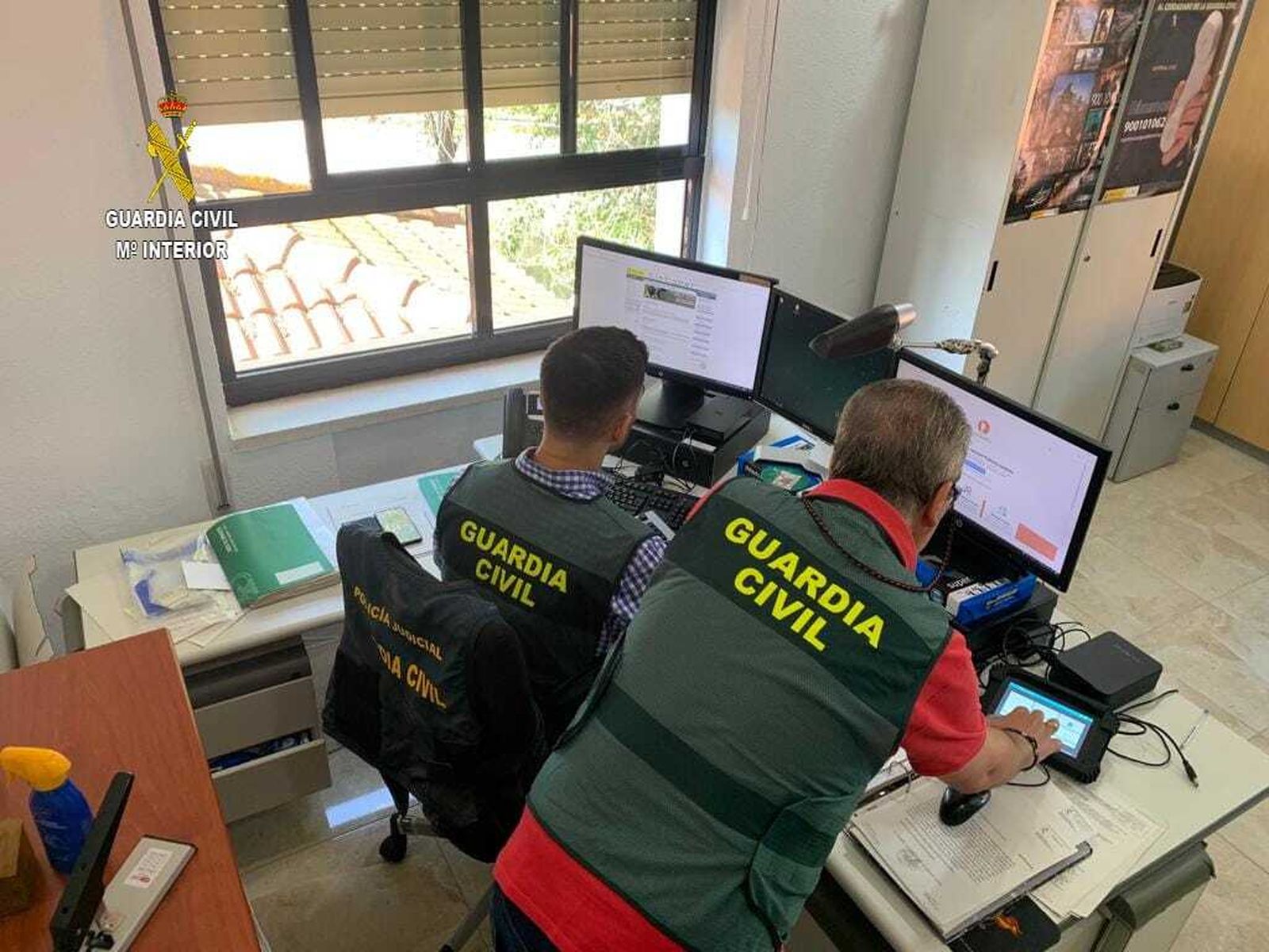 Agentes de la Guardia Civil hacen comprobaciones en dos ordenadores.
