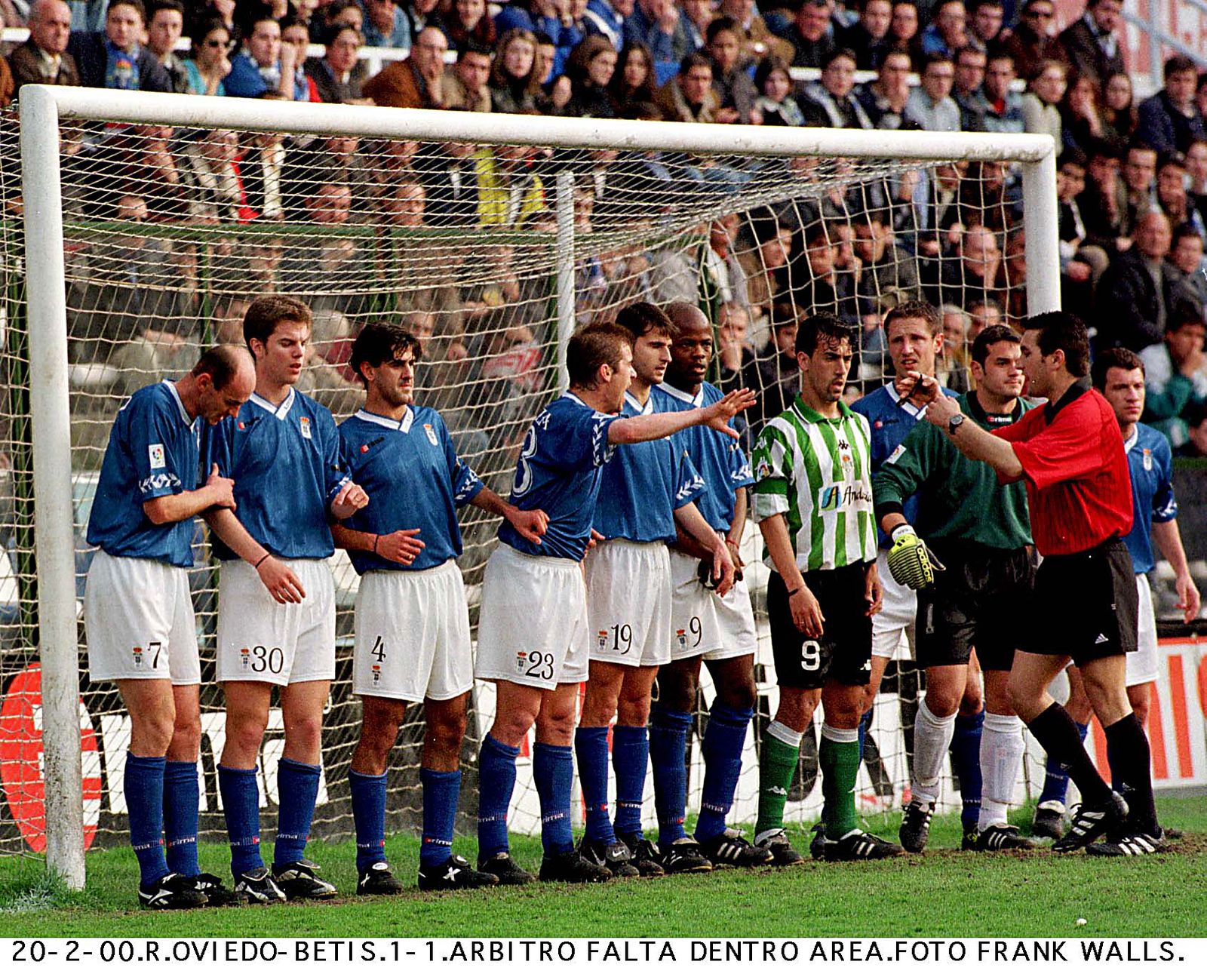El bético Oli se mete en una barrera del Oviedo con algunos jugadores azulinos conocidos, como el meta Esteban, Dely Valdés u Onopko, entre otros, en el Oviedo-Betis del año 2000.