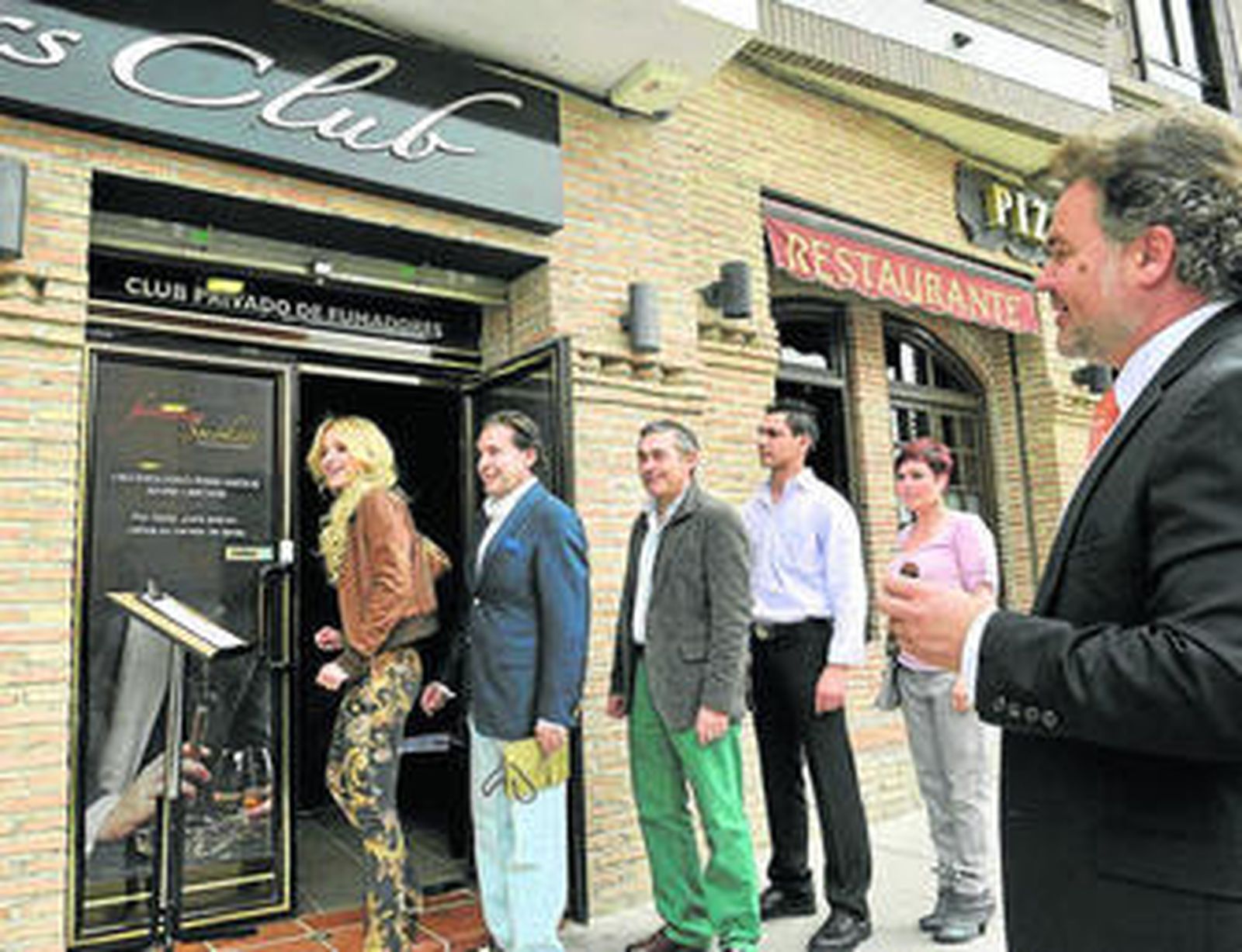 Varias personas hacen cola para inscribirse en el registro de socios a la entrada del local.