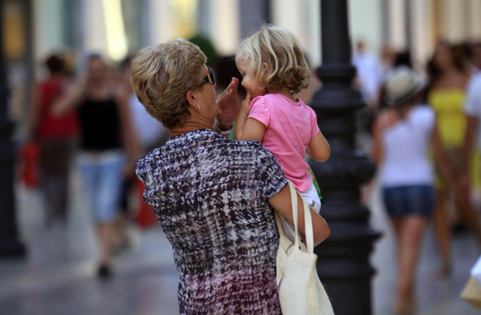 Una abuela lleva en brazos a su nieta.
