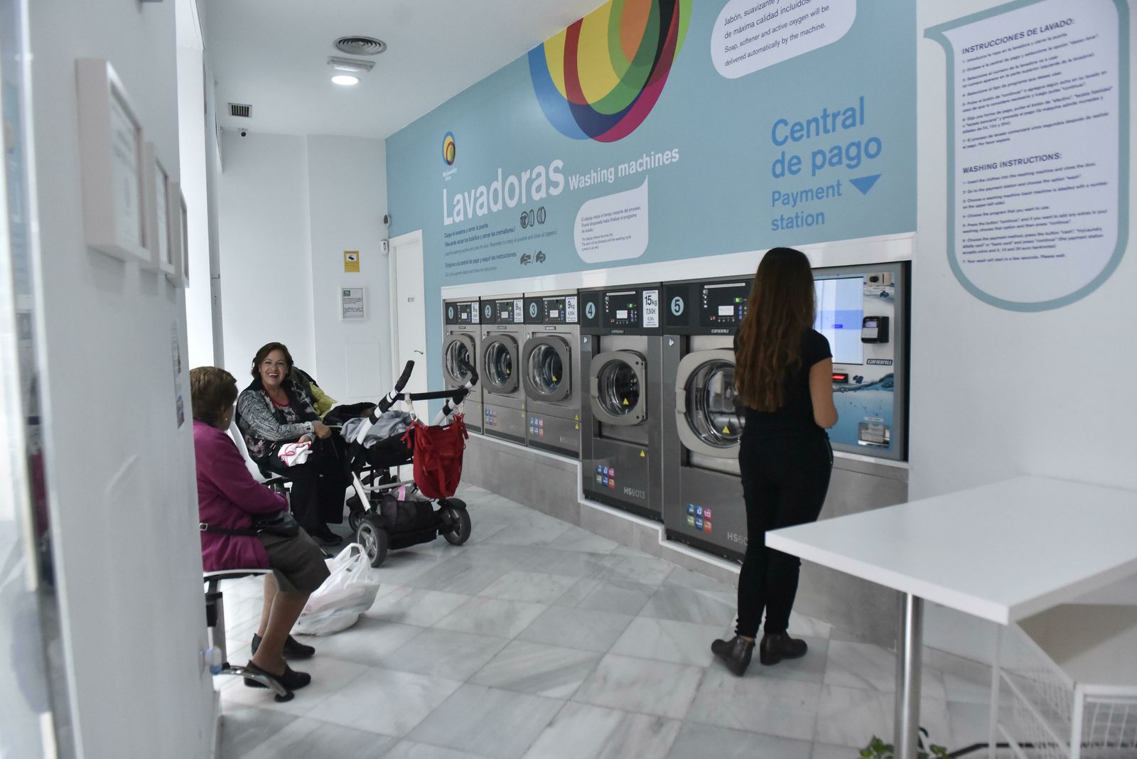 Tres mujeres esperan en una lavandería de Sevilla.