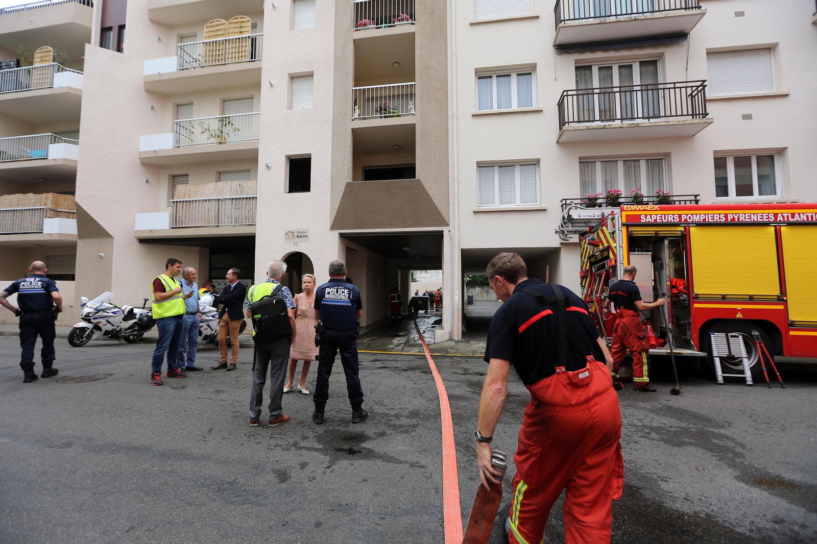 Bomberos y policías trabajan a las puertas del bloque de pisos donde ha tenido lugar el crimen en Pau.