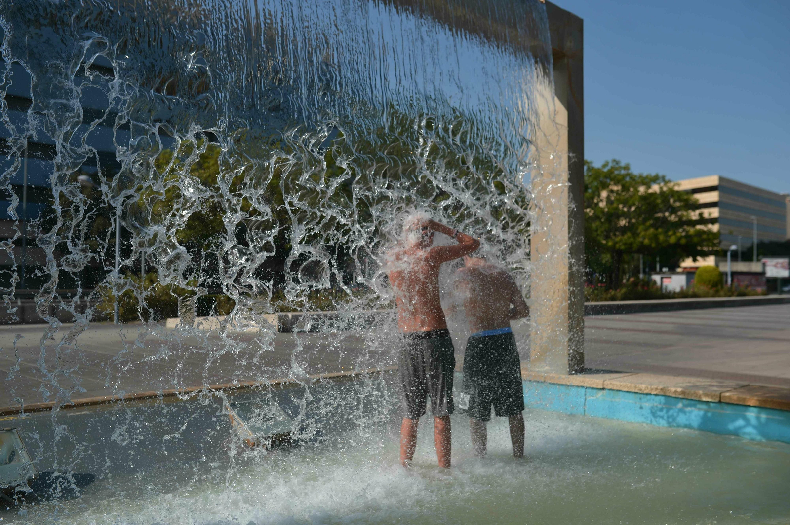 Dos jóvenes se refrescan en una de las fuentes del Plan Renfe.