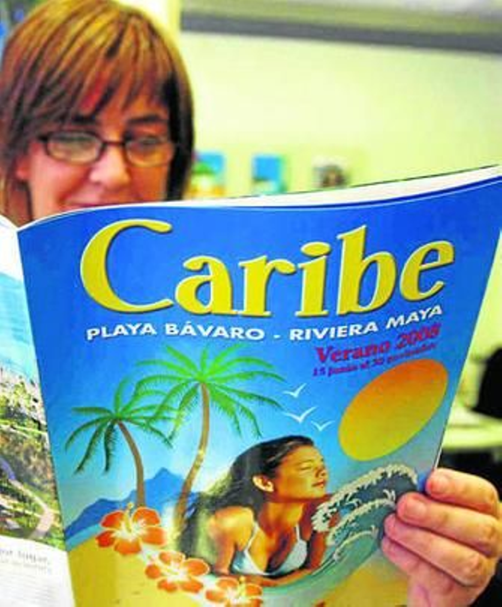 Una mujer lee un folleto de viajes al Caribe. Una mujer lee un folleto de viajes al Caribe.