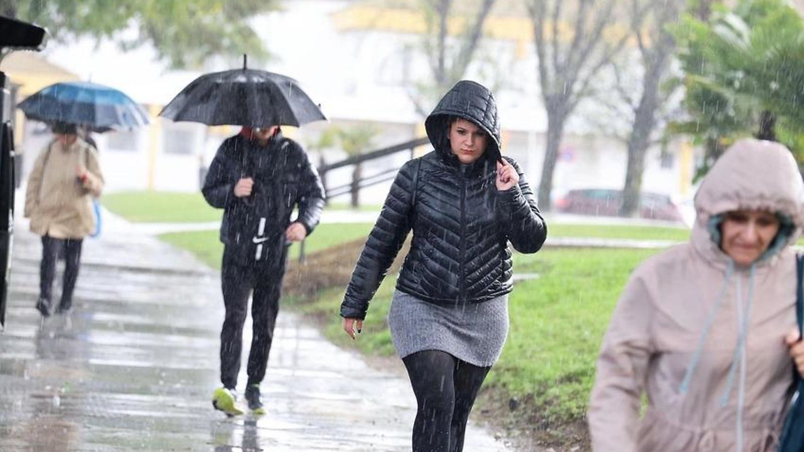 Personas tratan de resguardarse de la lluvia en Huelva.