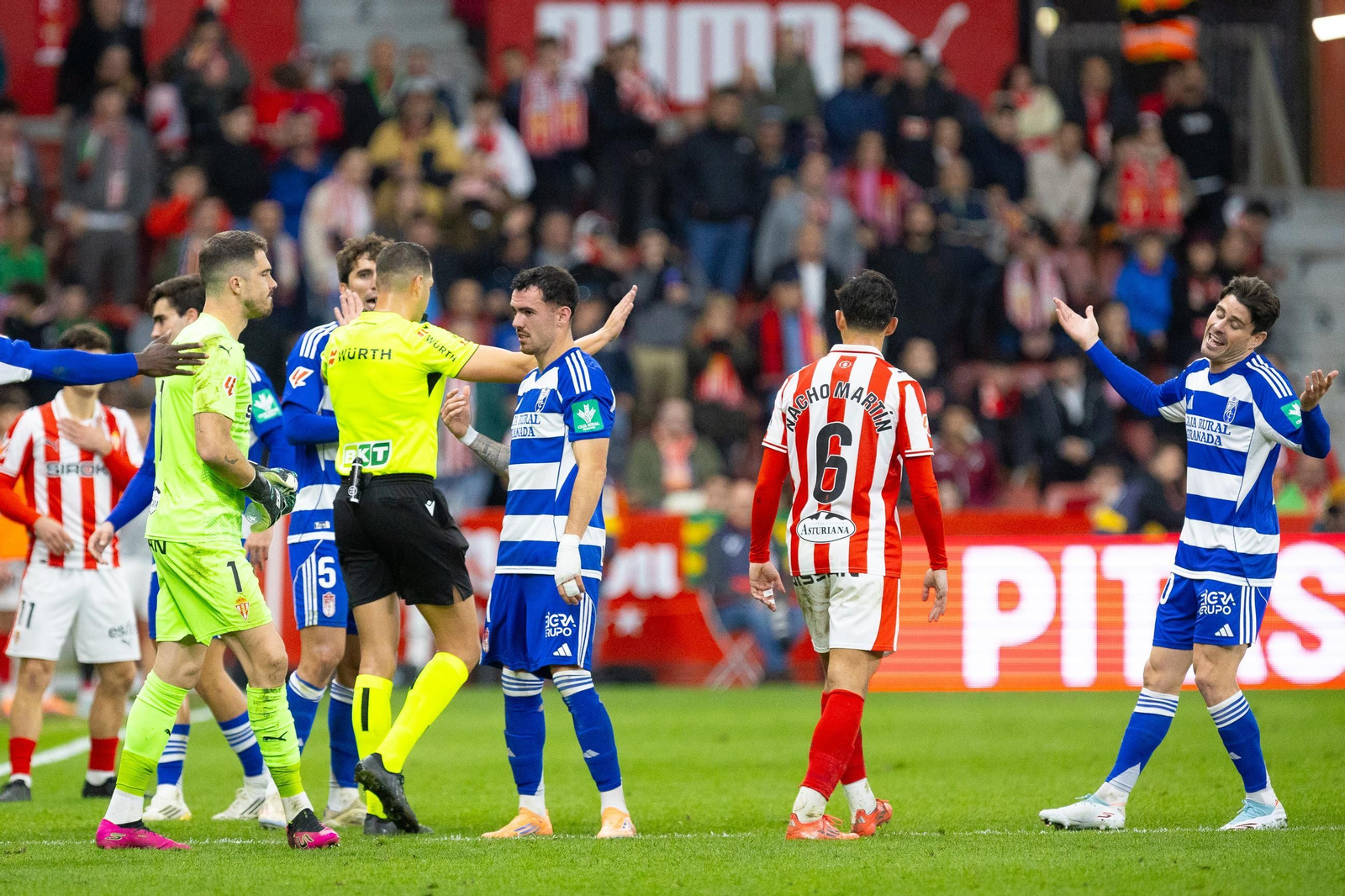 Los jugadores del Granada piden explicaciones al árbitro del partido ante el Sporting