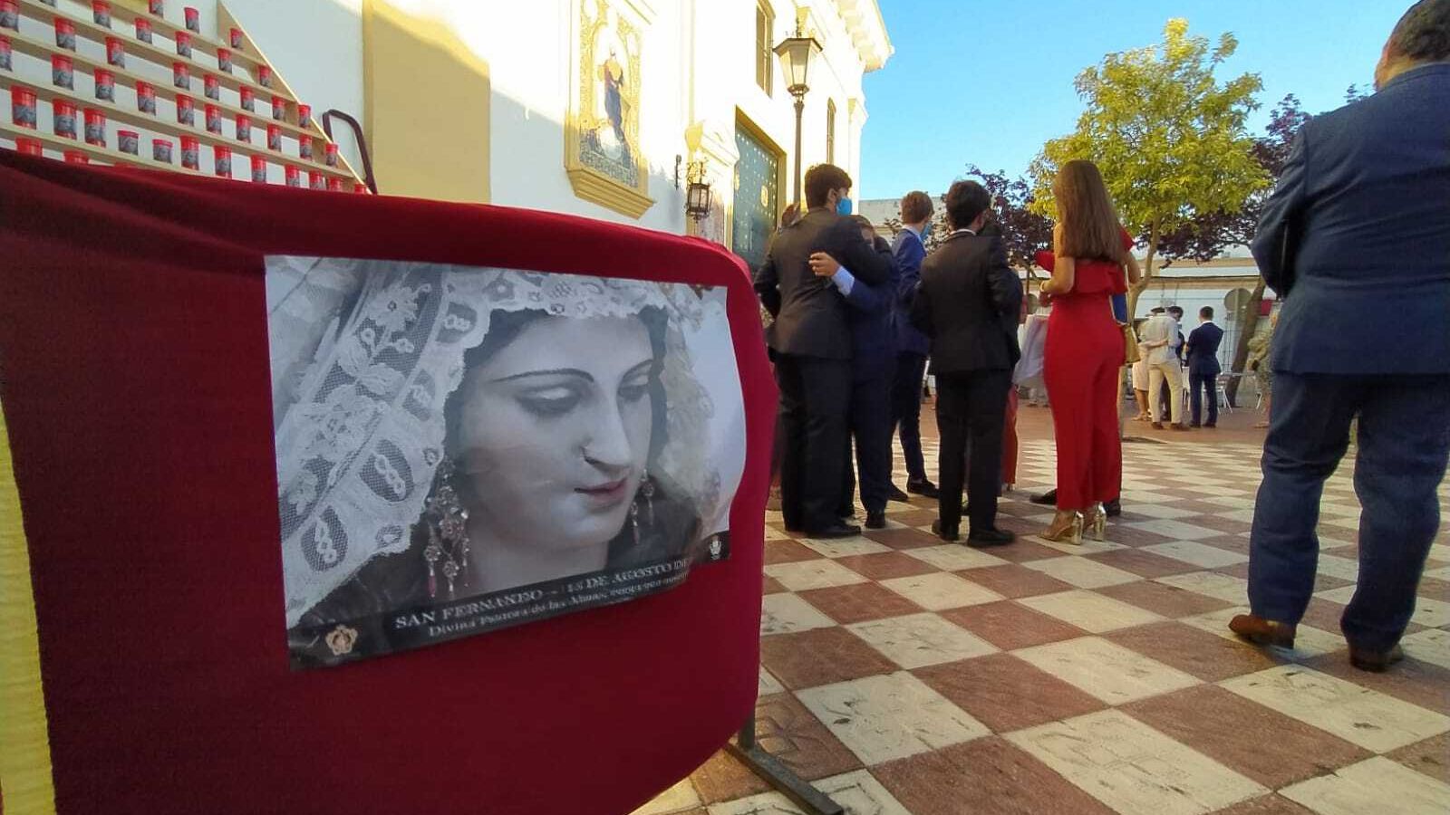 Miembros del grupo joven de la Pastora, en la plaza, junto a las velas que han colocado a los pies del  azulejo de la Virgen.