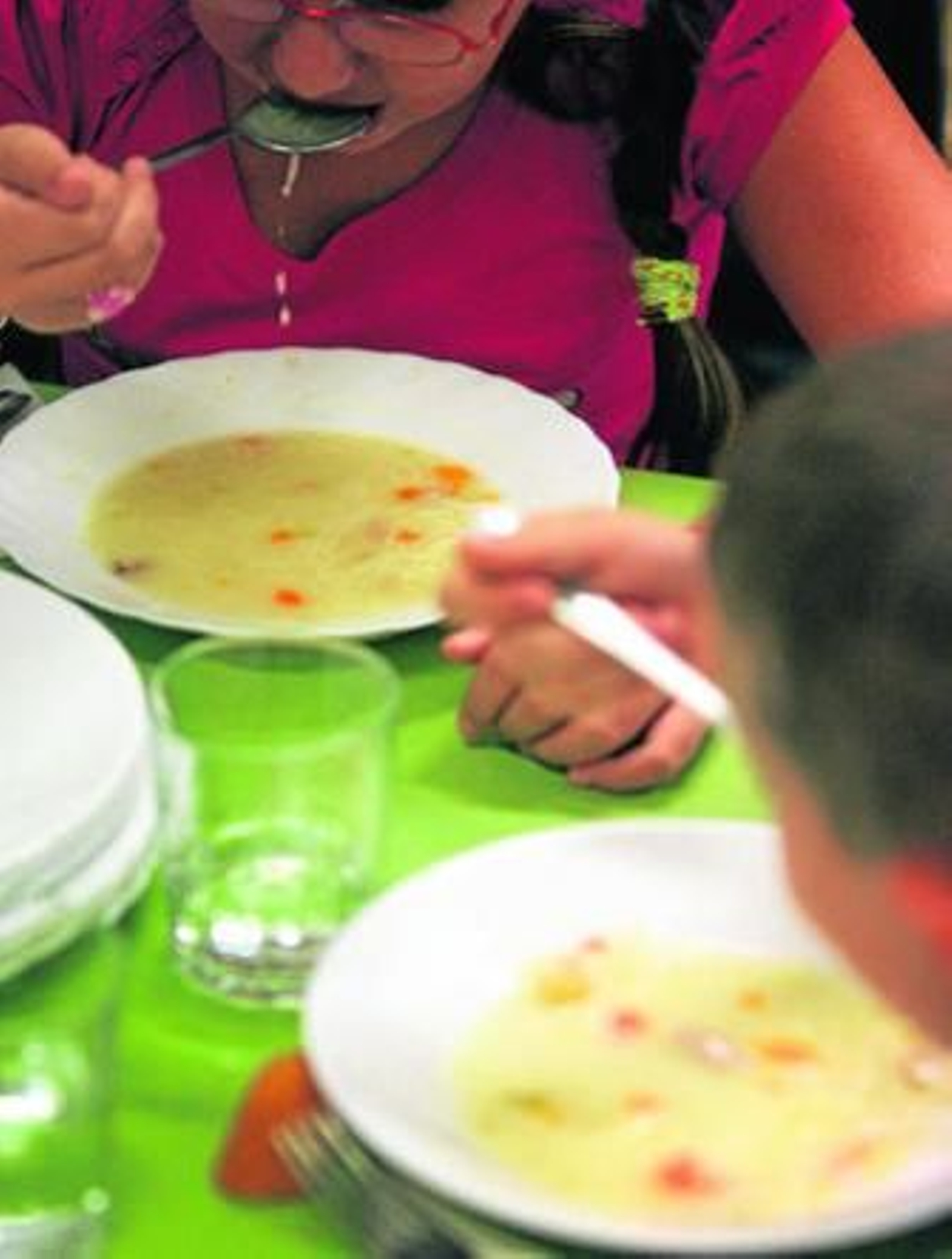Dos niños toman una sopa en un comedor escolar.