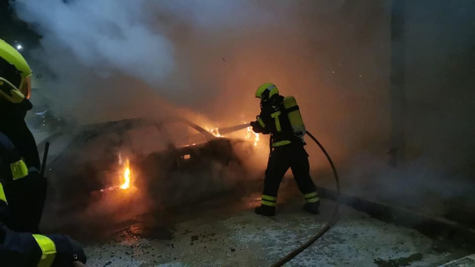 Los Bomberos apagan el fuego en un vehículo durante los disturbios de La Línea