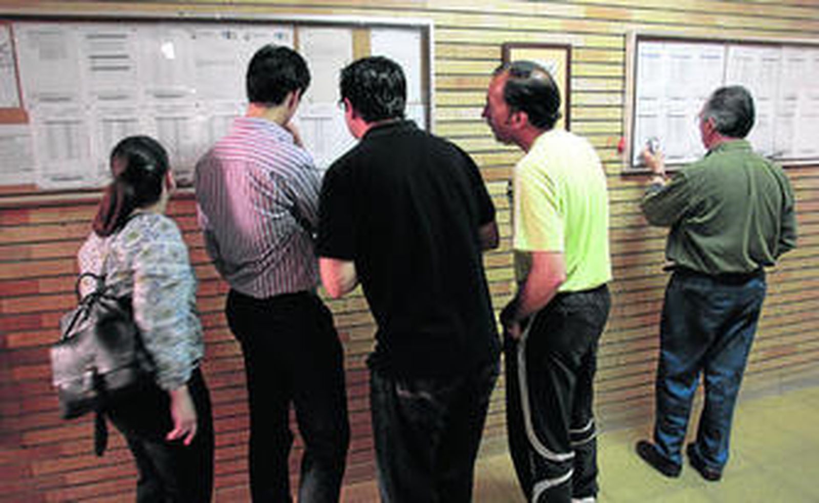 Un grupo de padres observa la lista de admitidos de un colegio.