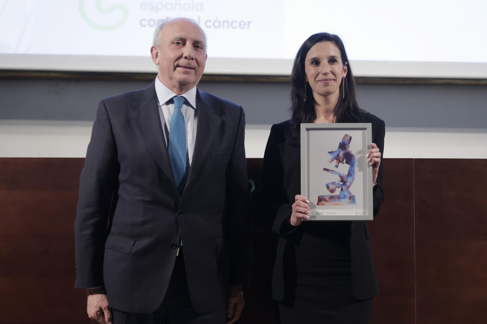 La investigadora de Cabimer Rosario Prados junto al premio que reconoce la obtención de la Ayuda Postdoctoral de la AECC.