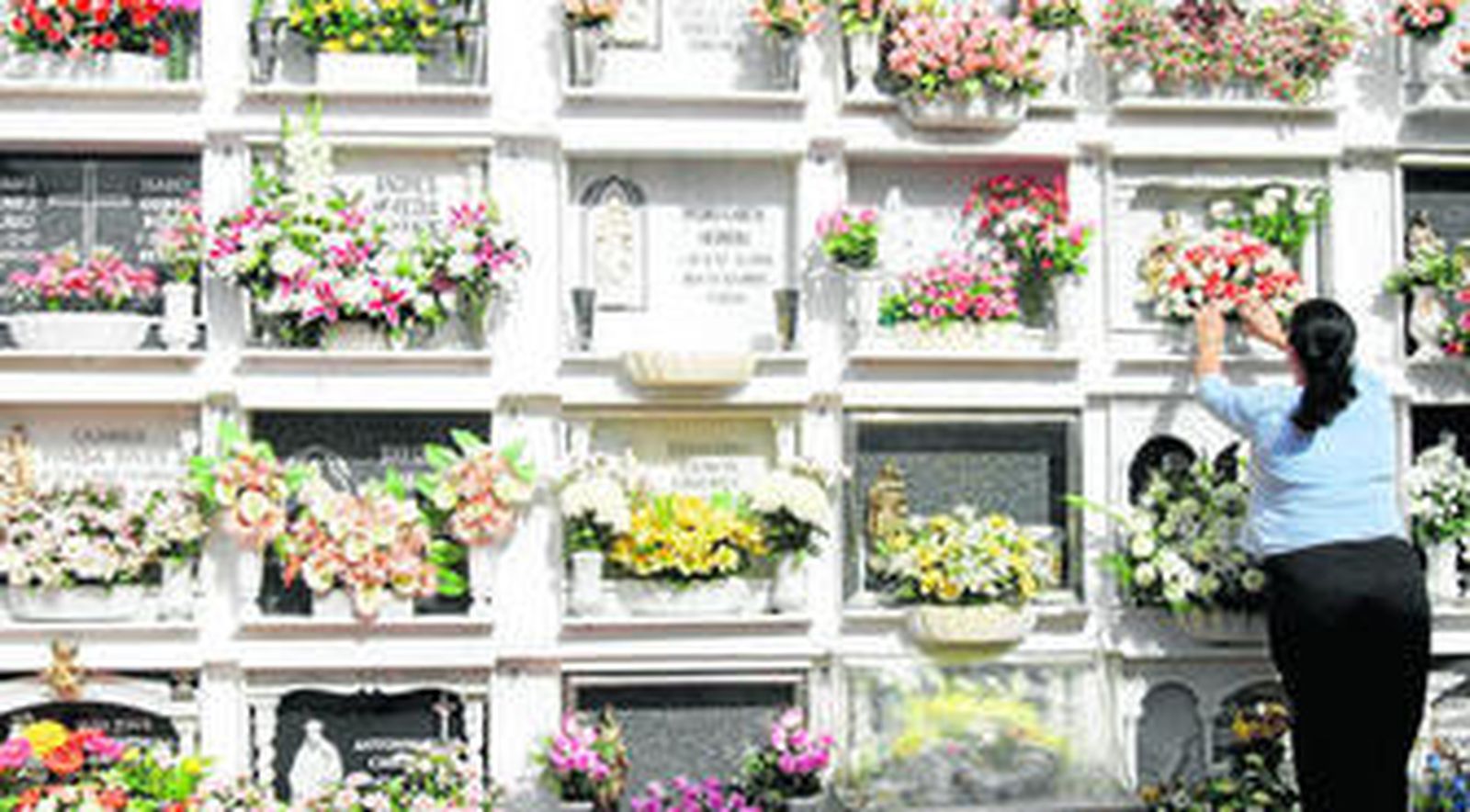 Una mujer coloca flores en una tumba del cementerio de San José, en una foto de archivo.