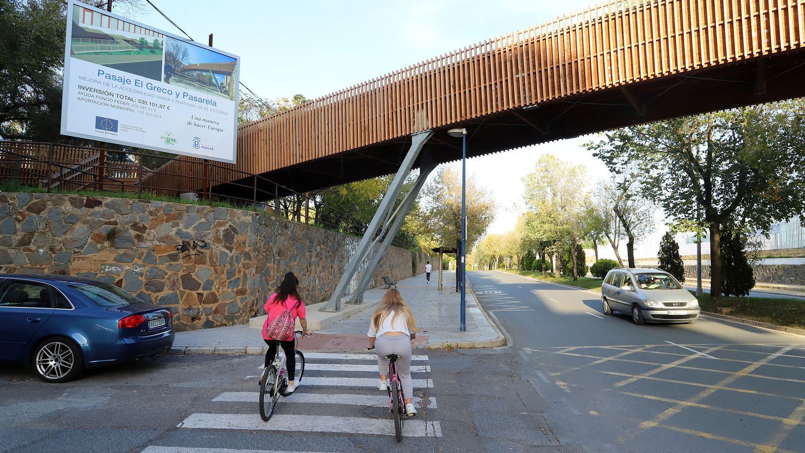 Dos ciclistas pasan bajo la pasarela.