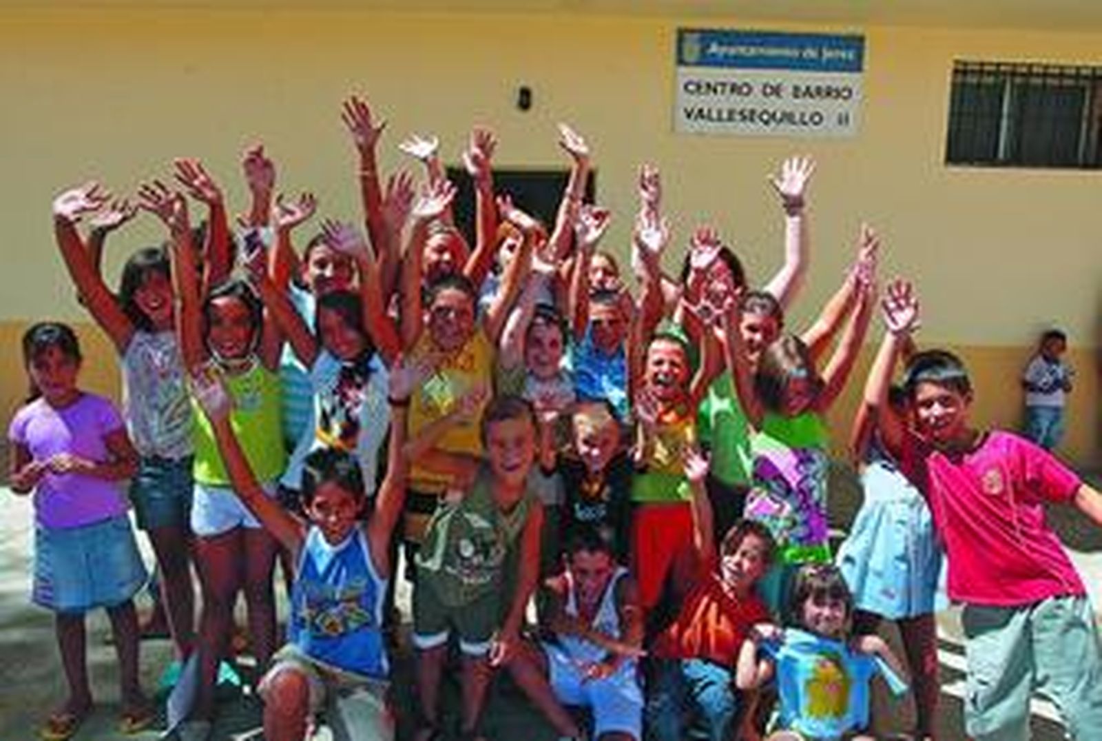 Un grupo de niños del centro de barrio Vallesequillo II, saludan contentos en el patio tras la jornada escolar veraniega.