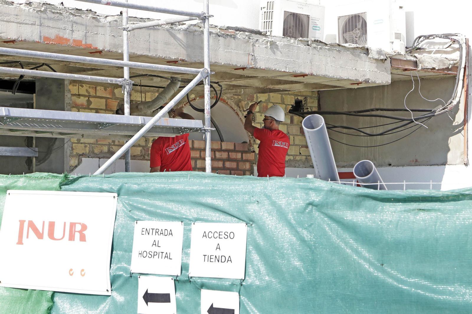 Dos obreros trabajan ayer en la marquesina de la entrada principal del hospital, que será similar a la del edificio de Radioterapia.
