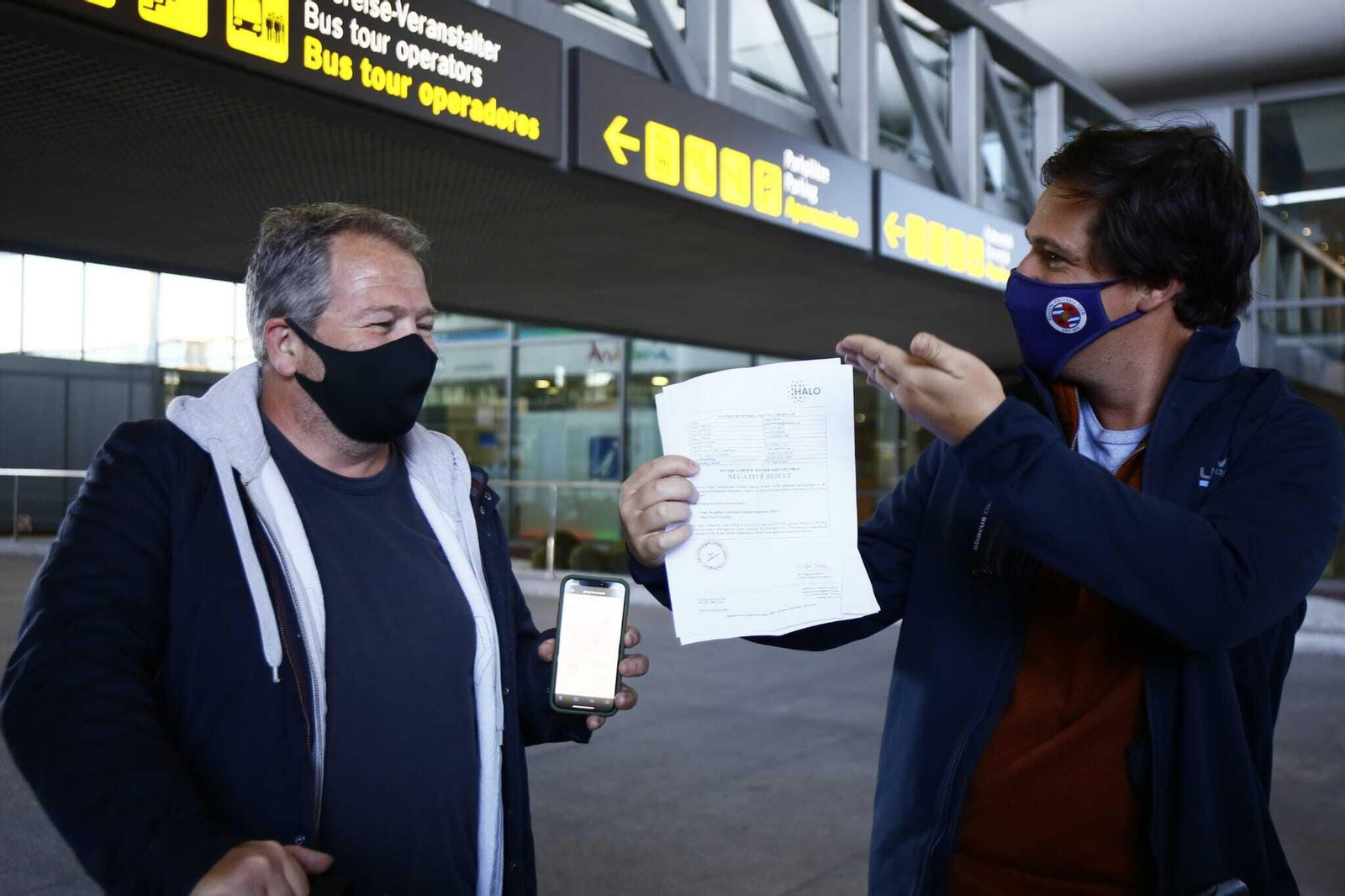 Robin Hewer y Edgar Morse muestran divertidos su test negativo tras llegar en un vuelo desde Londres.