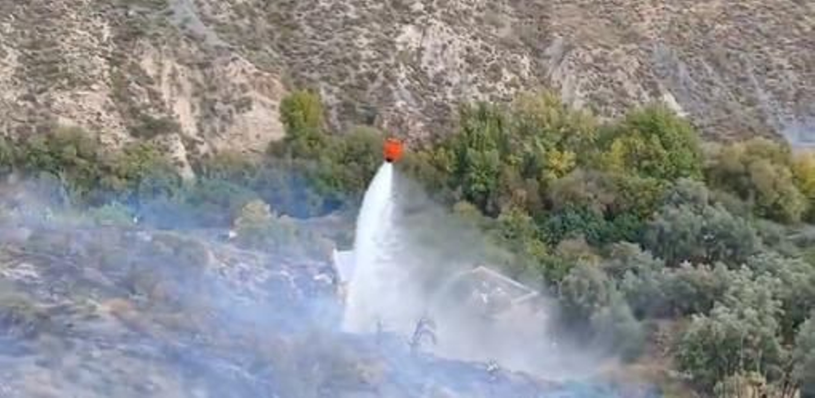 Un helicoptero descarga agua sobre el incendio.