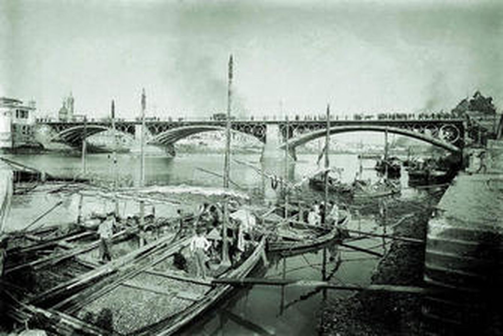 El Puente de Triana y la actividad en el Guadalquivir, en una fotografía sin fecha exacta de Lucien Roisin Bernard.