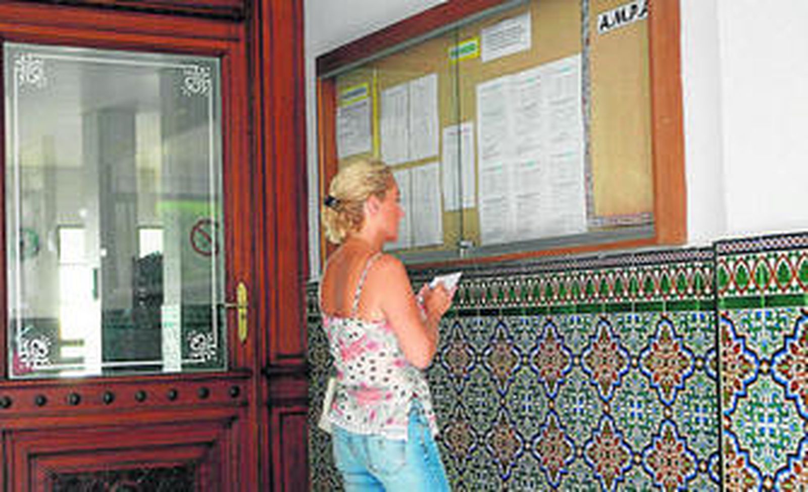 Una madre comprueba la puntuación de su hijo en un centro concertado.