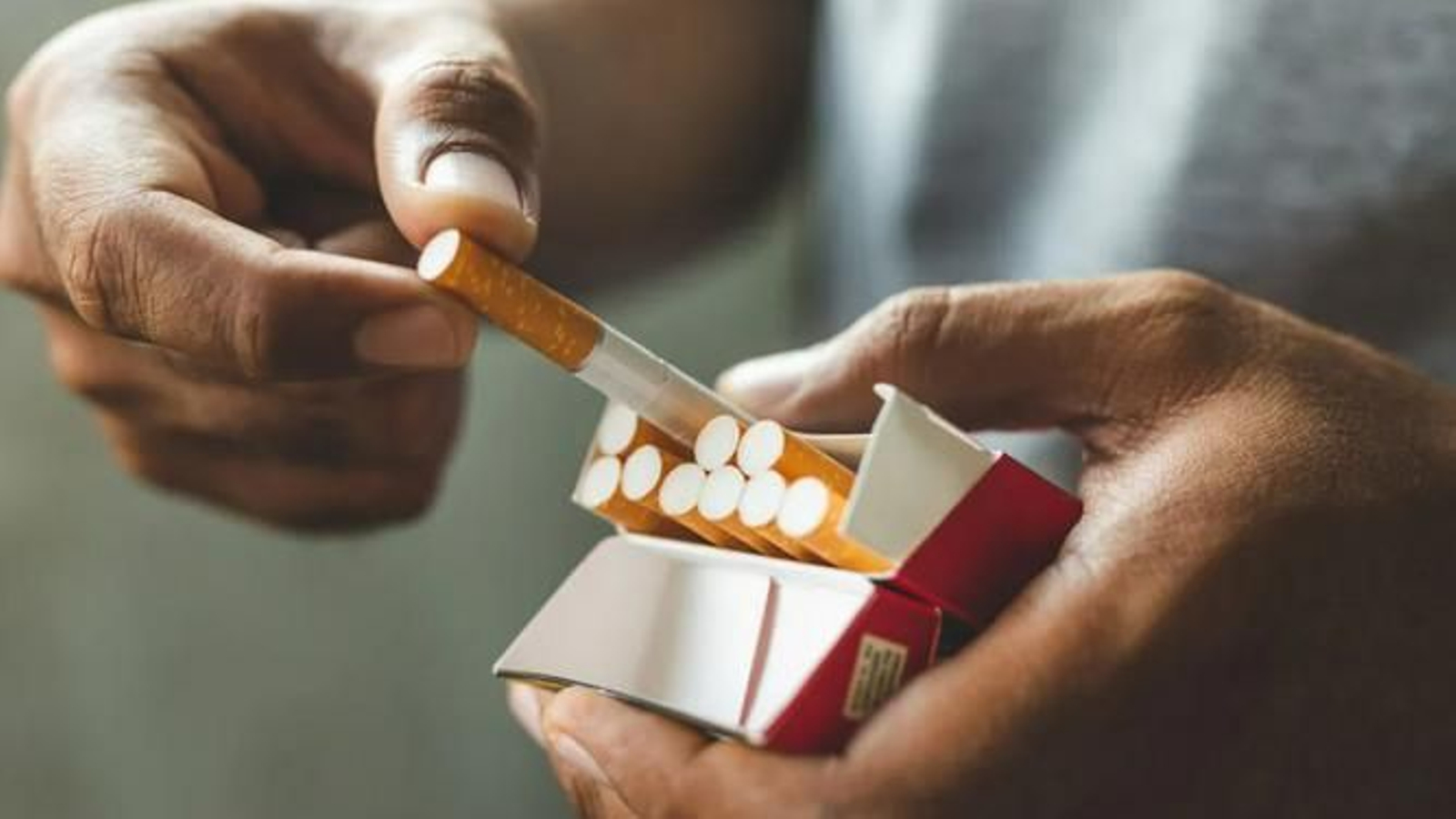 Un hombre sacando un cigarro de una cajetilla de tabaco