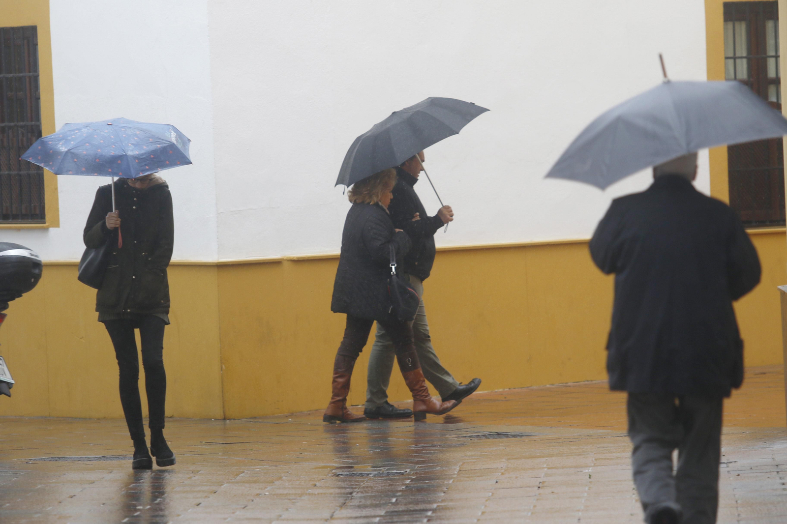 Varias personas se protegen de la lluvia y el viento.