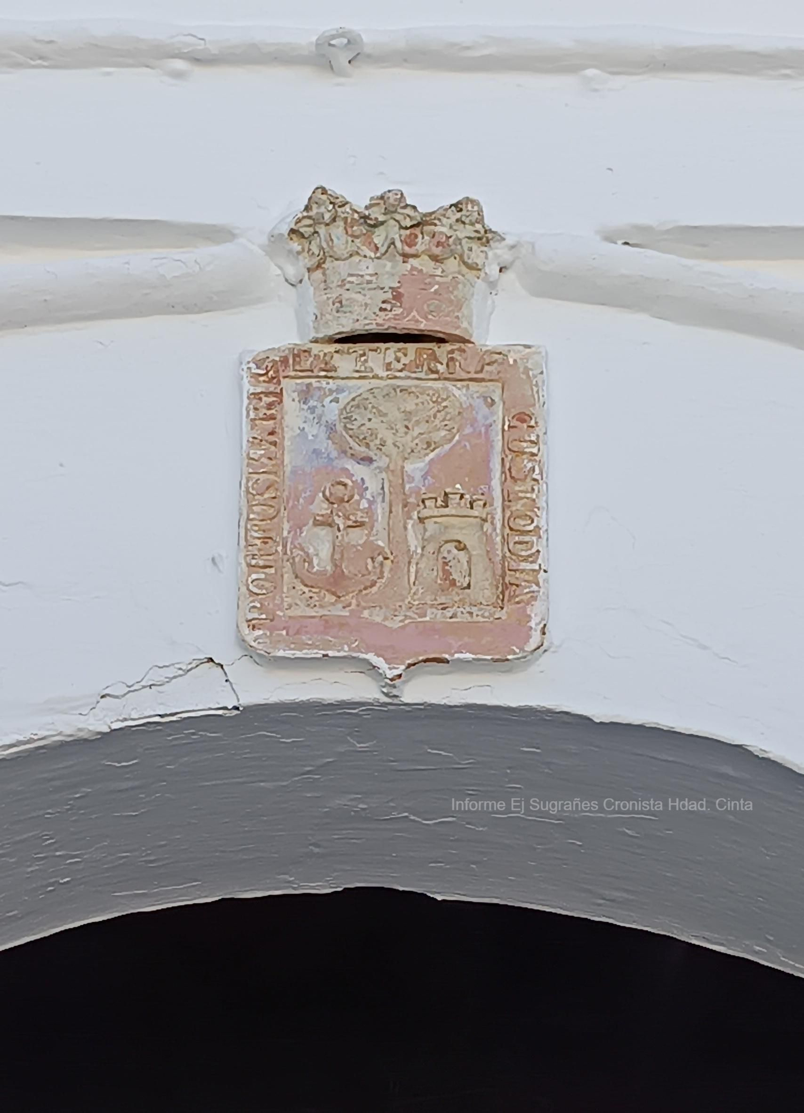 Escudo en barro cocido en el arco de entrada del claustro.