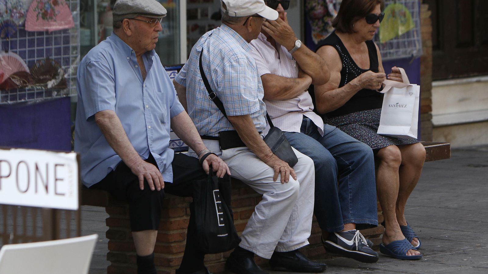 Un grupo de personas mayores descansa en un banco en el centro de la ciudad.
