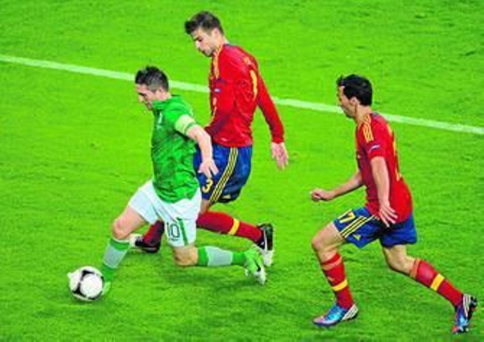 Robbie Keane controla hacia la banda mientras es encerrado por Piqué y Arbeloa.