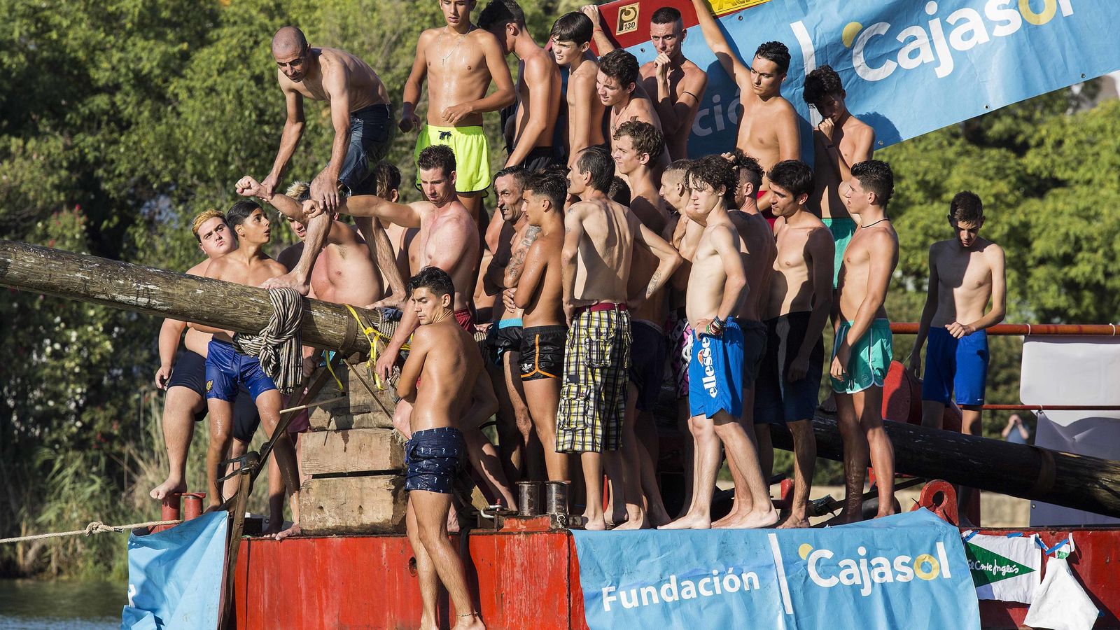 Un joven se apoya en dos compañero para lograr impulsarse.