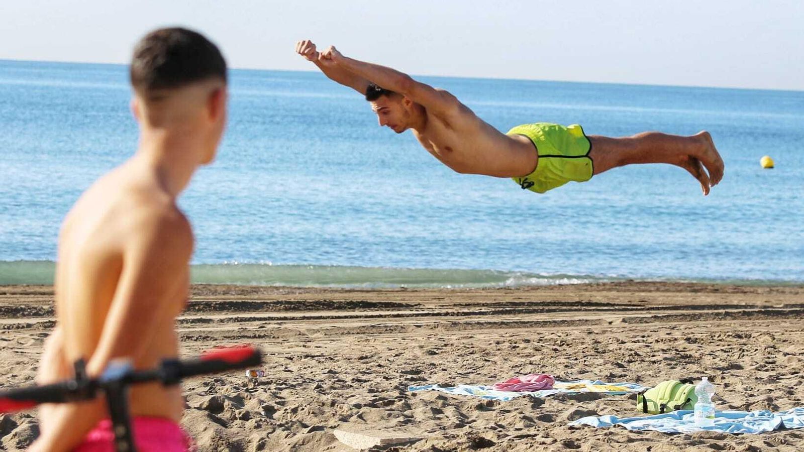 Un joven salta esta mañana en la arena en una playa en Málaga.