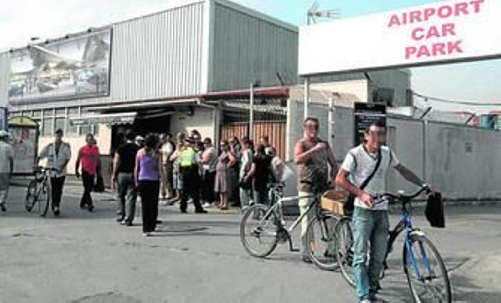 Una agente policial de Gibraltar ordena la cola de personas que esperan para comprar tabaco para que no entorpezcan el tráfico rodado.