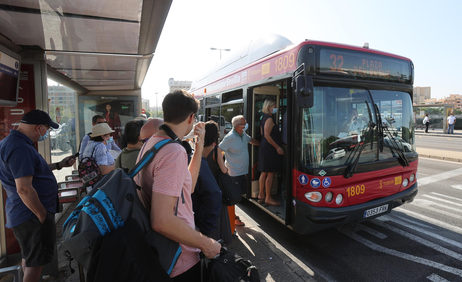 Un grupo de viajeros esperan para subir a un bus en Sevilla.