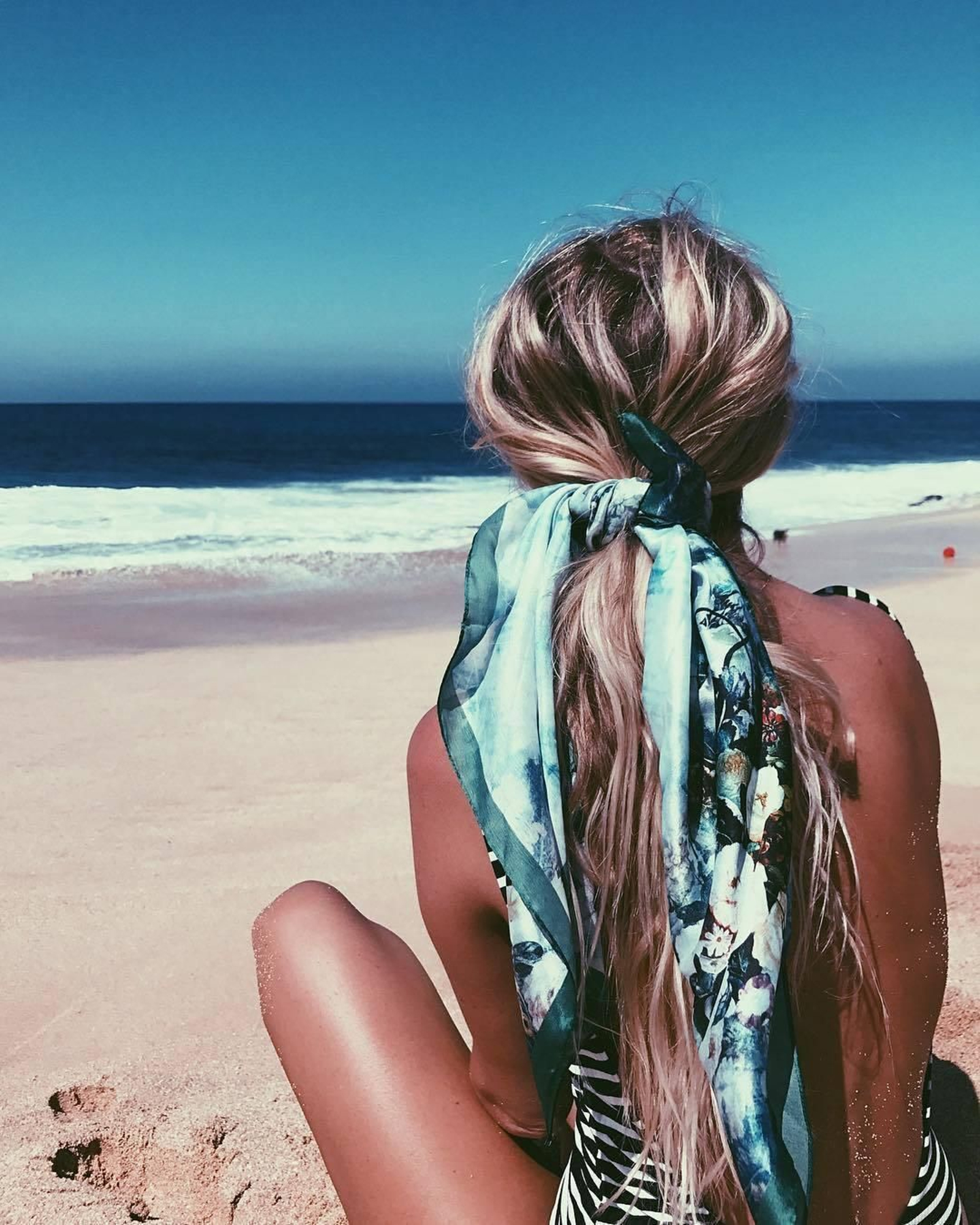 La coleta con pañuelo es uno de los estilismos más usados este verano, y no nos extrañamos cuando vemos que queda así de genial.  Simplemente recógete el pelo en una cola y cubre la goma con un pañuelo. También puedes hacer el recogido con el pañuelo directamente, pero de la otra es menos probable que se caiga.