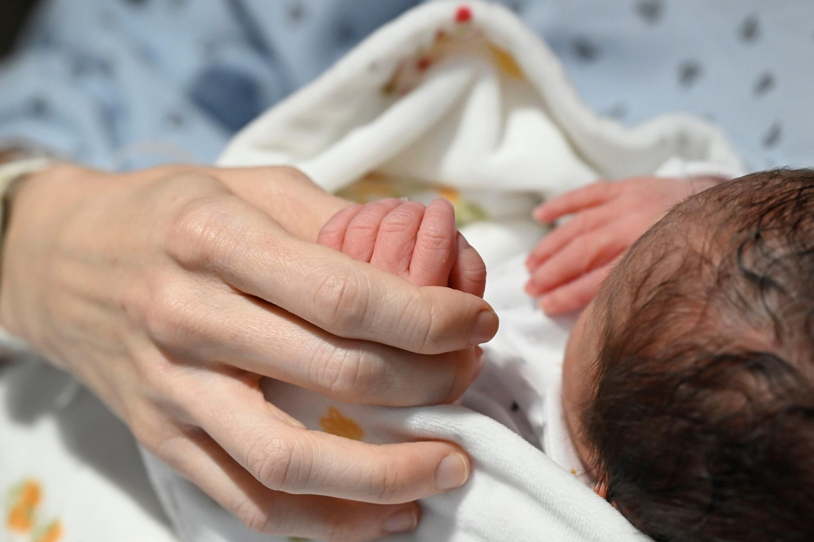 Una madre coge la mano de su bebé recién nacido.