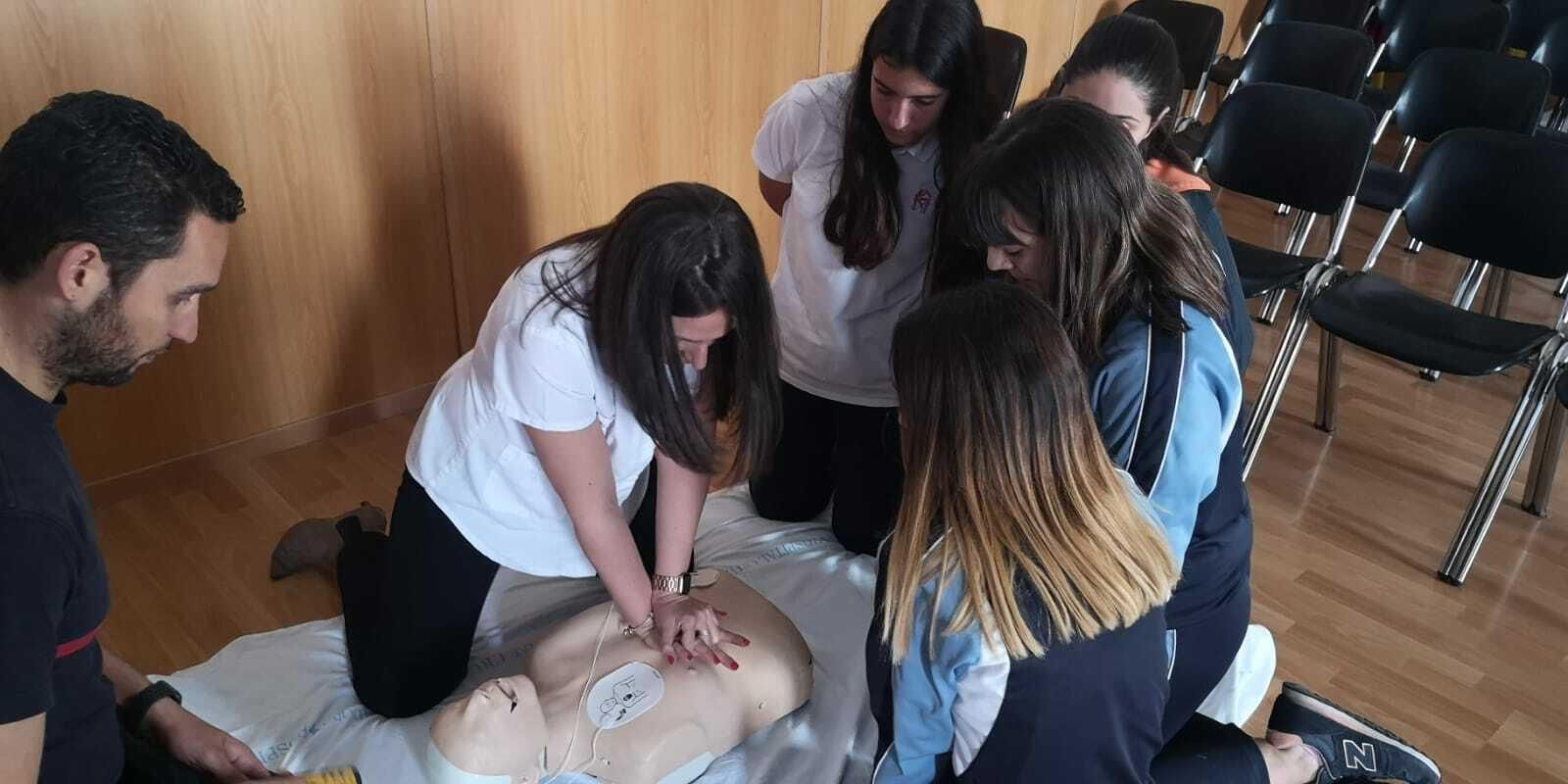 Alumnas del colegio La Inmaculada practican una RCP bajo la supervisión del personal de Cruz Roja.