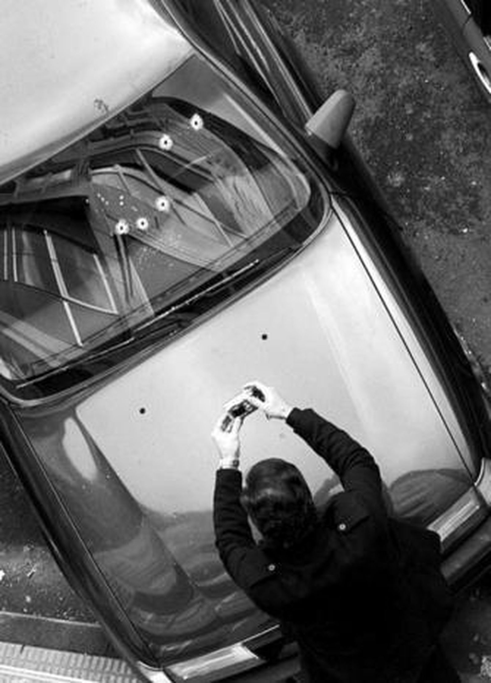 Un miembro de la Ertzaintza toma fotografías de los impactos en el coche de Carrasco.