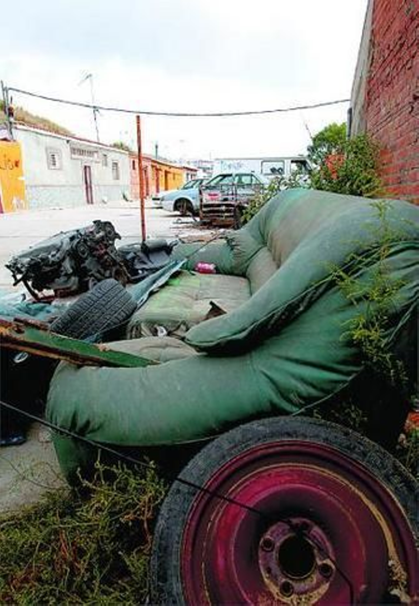 Un sofá y un motor de coche tirados en la barriada de Pajarete.