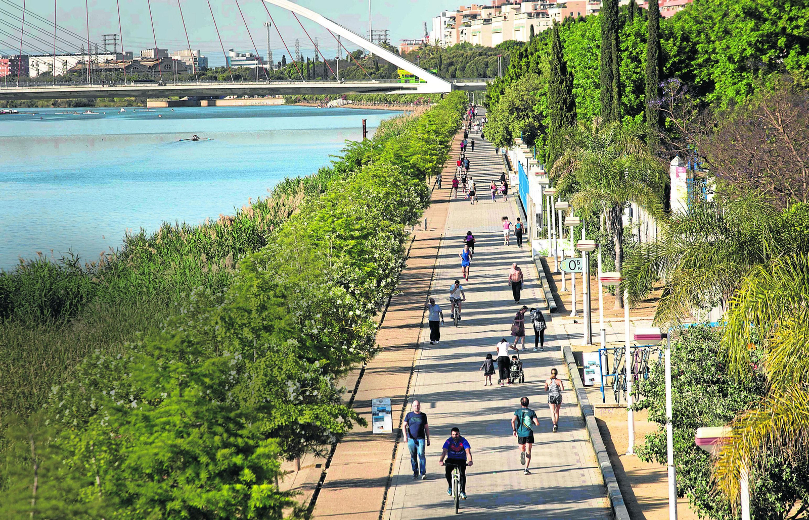 Viandantes pasean junto al río Guadalquivir.