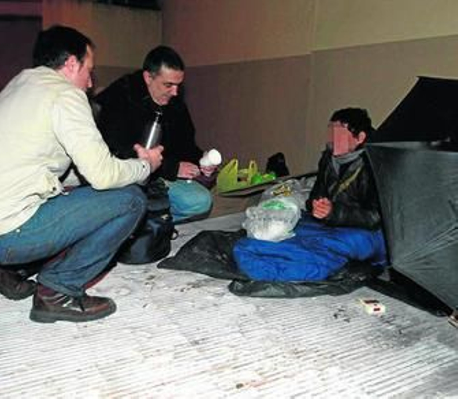 Voluntarios de Cáritas llevan una bebida caliente a una indigente en una fotografía de archivo.