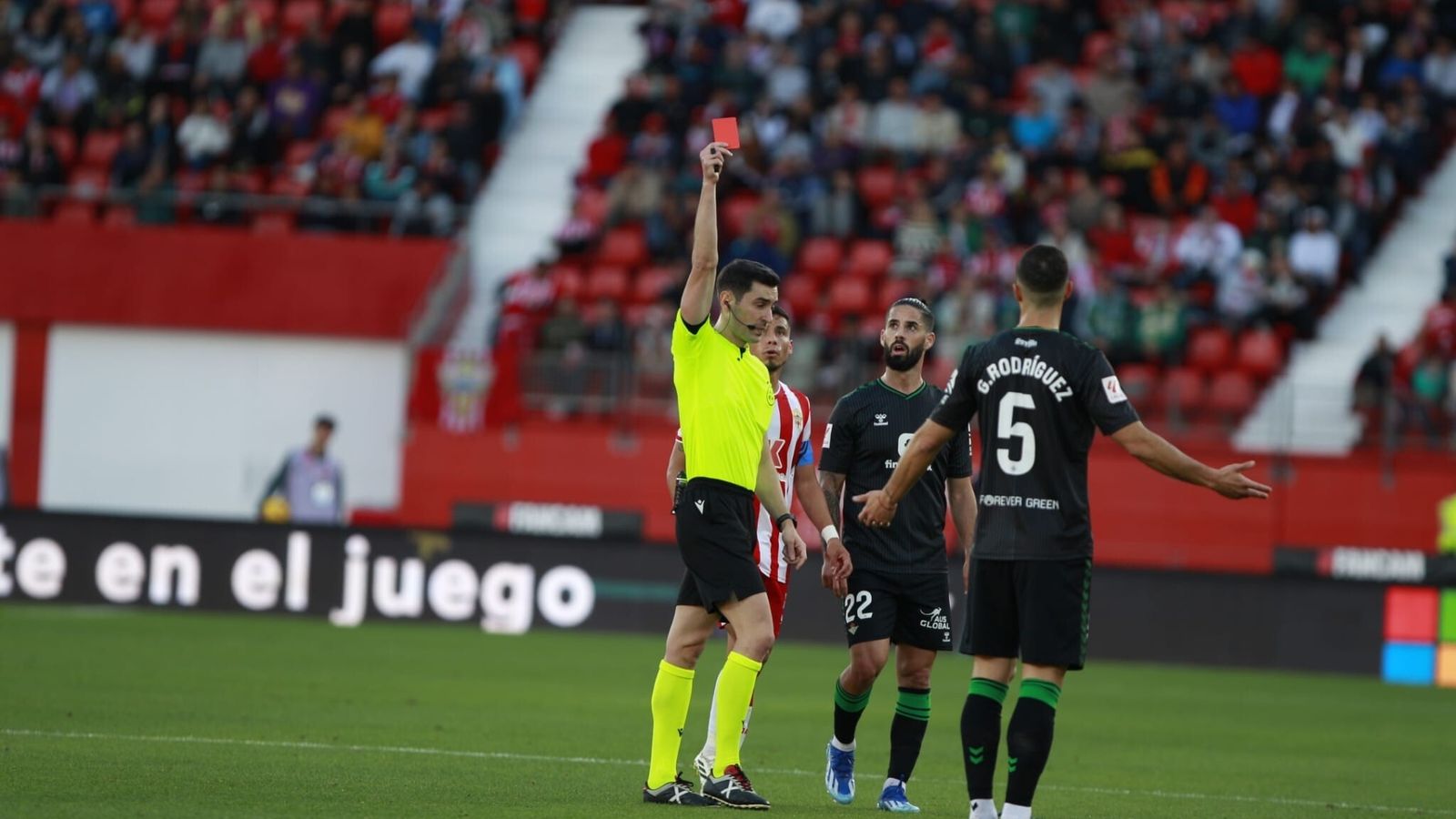 Muñiz Ruiz muestra la cartulina roja entre el asombro de Isco y la protesta de Guido Rodríguez.