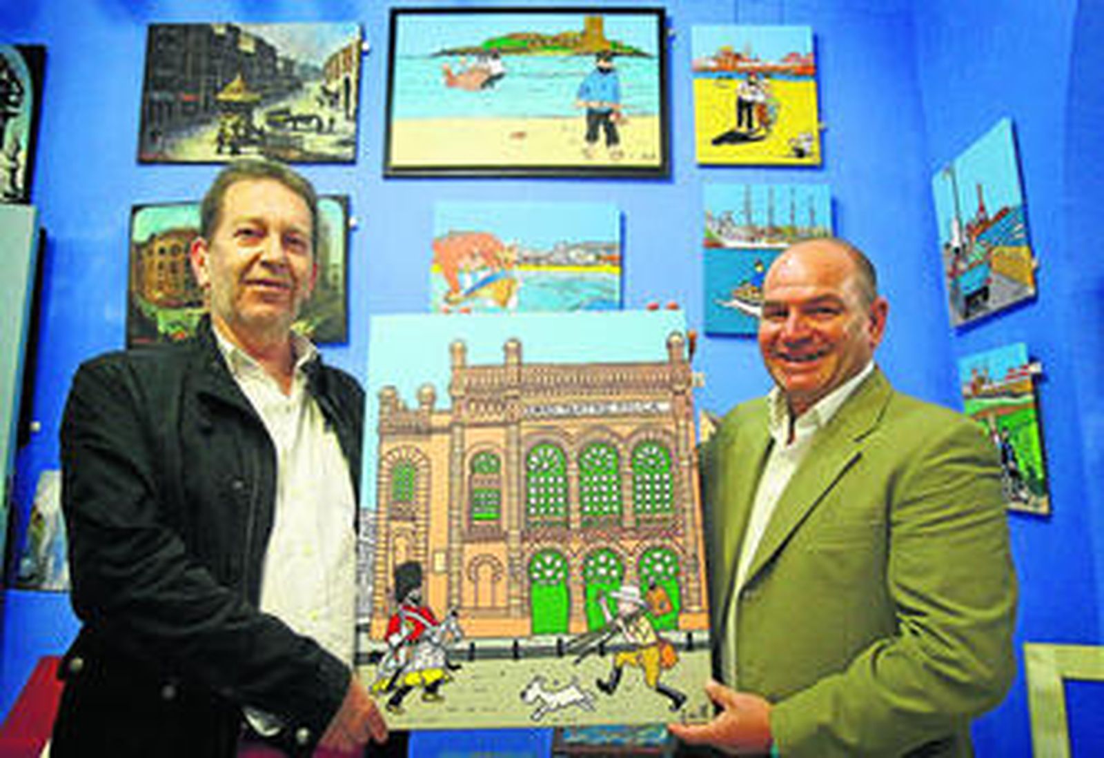 Emilio Jiménez e Iñaki Blanco muestran una de sus obras con los personajes de Hergé corriendo frente al Teatro Falla.