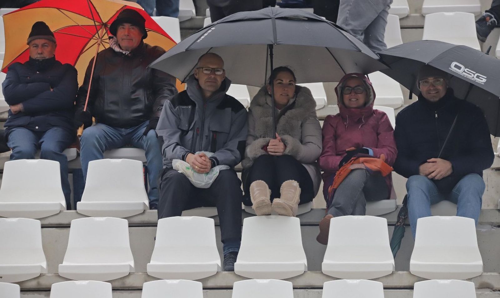 Aficionados se protegen de la lluvia durante el Balona-Córdoba B