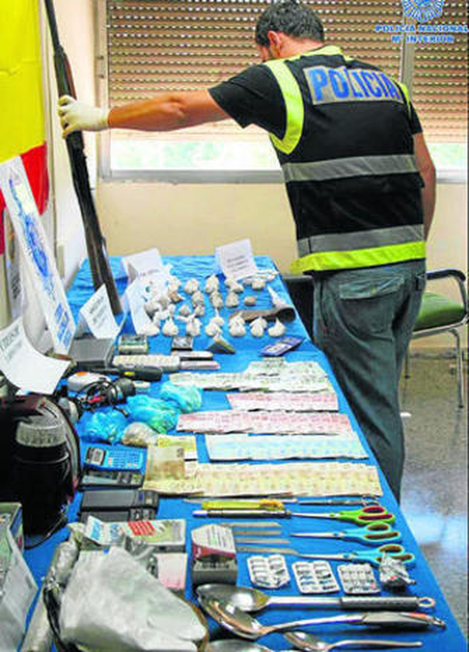 Un policía sostiene una de las escopetas intervenidas, con el material incautado en una mesa.