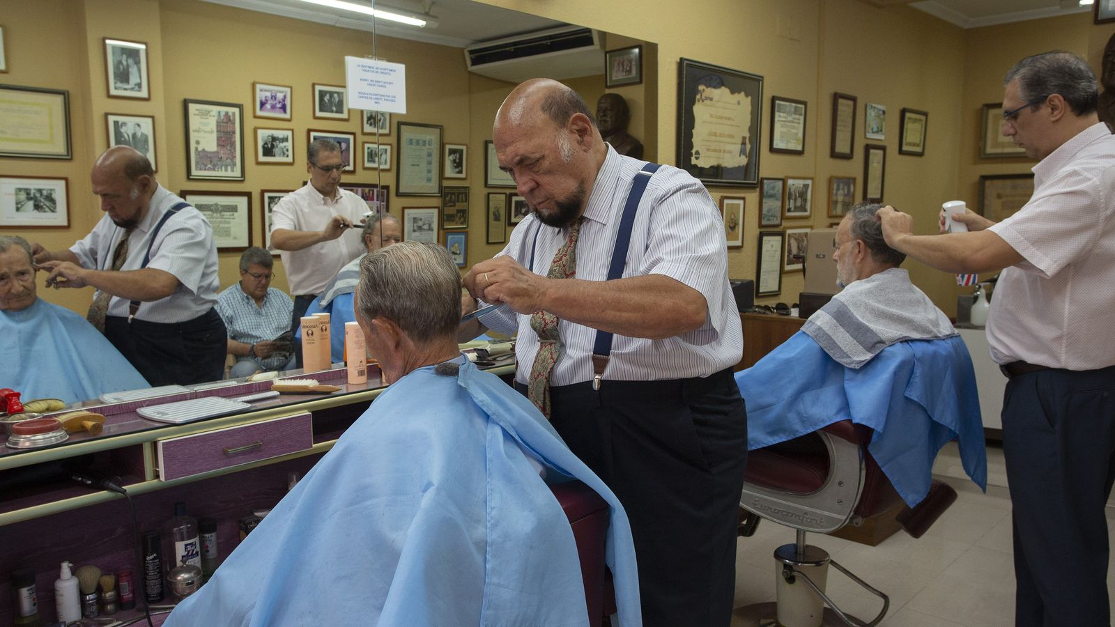 Manuel  Melado arreglándole el pelo a un cliente.