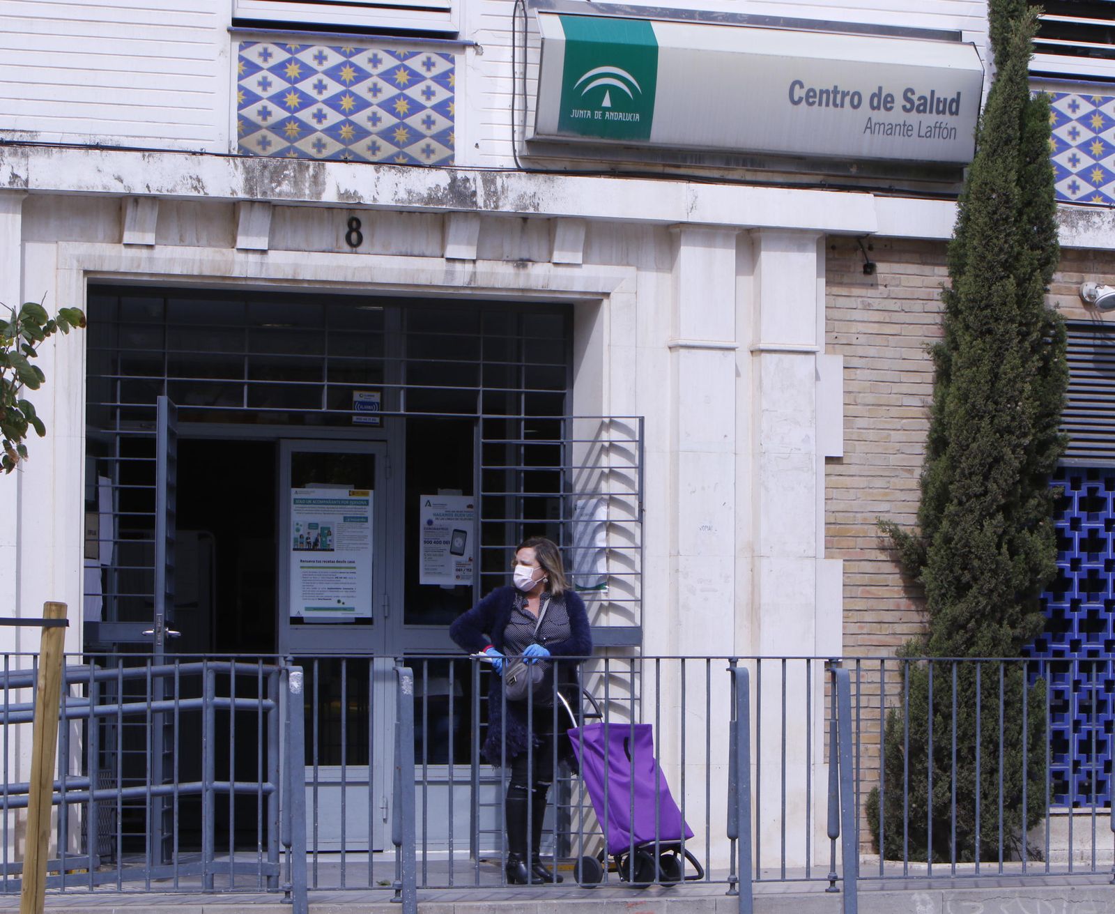 Una mujer con guantes y mascarilla, a las puertas de un centro de salud.
